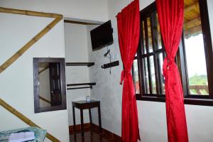 a room with red curtains and a tv on a wall at Hospedaje y Camping Buena Vista in San Agustín