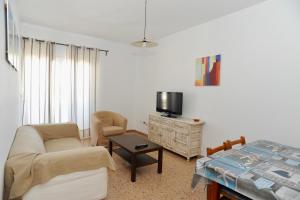 sala de estar con sofá, silla y TV en Viviendas Turisticas S'Estanyol, en La Savina