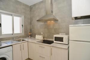 a kitchen with a white refrigerator and a microwave at Viviendas Turisticas S'Estanyol in La Savina