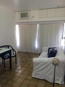 a living room with a white bed and a table at Flat em Ondina (ap.404) in Salvador