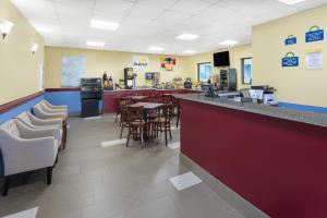 a restaurant with a bar and tables and chairs at Days Inn & Suites by Wyndham Peachtree Corners Norcross in Norcross