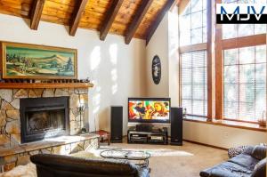 een woonkamer met een open haard en een televisie bij Chateau Bernina in Lake Arrowhead