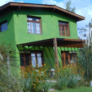 una casa verde con ventanas y flores delante de ella en Celandine en Los Reartes