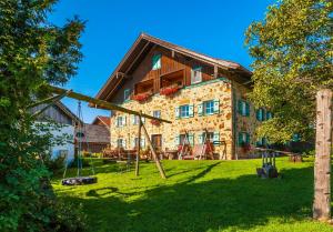 una casa con un parque infantil delante de ella en Baby- und Kinderhof Aicherbauer, en Seeham