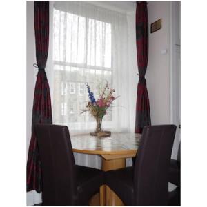 a dining room table with chairs and a vase of flowers on it at Goldenacre Private Room (Homestay) in Edinburgh