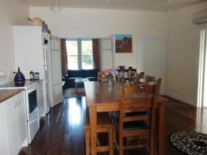 uma cozinha e sala de jantar com uma mesa de madeira e cadeiras em Oamaru Green Cottage em Oamaru