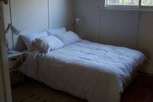 a bed with white sheets and pillows in a bedroom at Loutit Views in Lorne