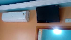a television and a air conditioner on a wall at Hotel Golf II - SOB NOVA DIREÇÃO - CRUZEIRO in São Paulo
