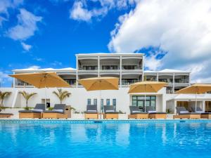 a resort with a swimming pool with chairs and umbrellas at The Loren at Pink Beach in Tuckerʼs Town