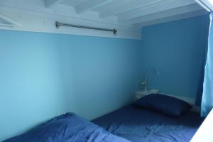 a blue room with a bed and a lamp at Hostel NABLA in Niijimamura