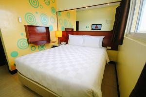 um quarto com uma cama grande e uma televisão em Go Hotels Tacloban em Tacloban