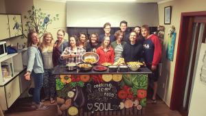 een groep mensen die rond een tafel met eten staan bij Bazil's Backpackers BBH Hostel & Surf School in Westport