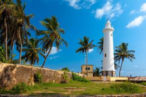 a lighthouse on the beach with palm trees at Villa Aroshina with cooking class in Galle