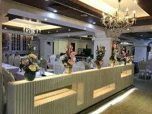 - une salle de banquet avec des tables blanches, des chaises et des fleurs dans l'établissement Fuhao Hotel, à Canton