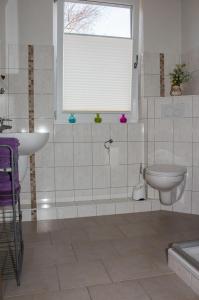ein Bad mit einem Waschbecken, einem WC und einem Fenster in der Unterkunft Gästehaus Margareth in Büsum