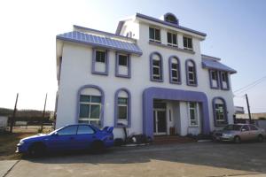 um carro azul estacionado em frente a uma casa branca em 驫風民宿 Equuleus Homestay em Magong