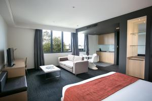 a hotel room with a bed and a living room at Alpha Hotel Eastern Creek in Blacktown