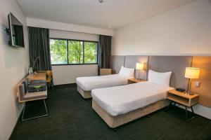 a hotel room with two beds and a window at Alpha Hotel Eastern Creek in Blacktown