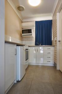 
a kitchen with a sink, microwave and refrigerator at Jefferys Motel in Toowoomba
