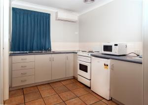 
a kitchen with a stove top oven and a microwave at Jefferys Motel in Toowoomba
