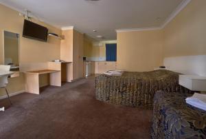 um quarto de hotel com duas camas e uma televisão de ecrã plano em Jefferys Motel em Toowoomba