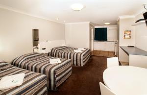 Jefferys Motel في توومبا: غرفة فندقية بسريرين وطاولة