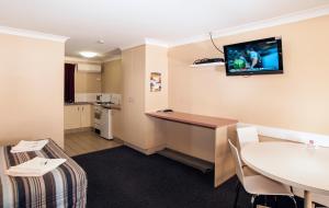 a room with a desk and a table and a kitchen at Jefferys Motel in Toowoomba