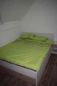 Una cama con sábanas verdes y almohadas verdes. en Borovnica Čatež, en Čatež ob Savi