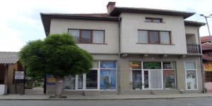 a building on a street with a tree in front of it at Proboyski Guest House in Tryavna
