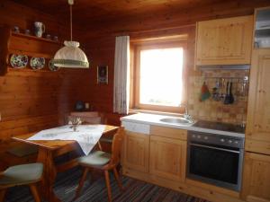 eine Küche mit einem Tisch, einem Waschbecken und einem Fenster in der Unterkunft Bauernhof im Wiesengrund in Maria Luggau