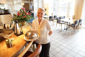 Dorint Parkhotel Bad Zurzach في باد زورزاخ: امرأة تقف بجوار طاولة في مطعم