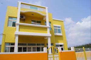a yellow building with a white fence in front of it at Penghu Le You You Homestay in Magong