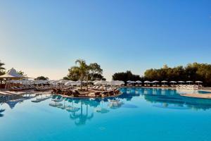 een groot zwembad met stoelen en parasols bij Grecian Park in Protaras