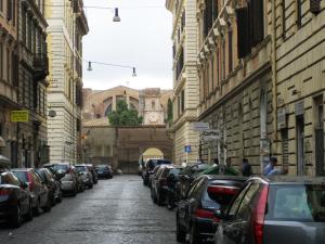 a city street with parked cars and a building with a clock at Bbqueen in Rome