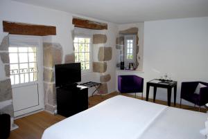 a bedroom with a bed and a desk and windows at Hotel Le Temps De Vivre in Roscoff
