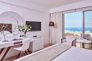 a white hotel room with a desk and a bed at Grecian Park in Protaras