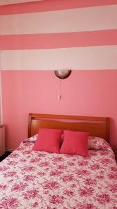 1 cama con 2 almohadas rojas y pared rosa en Pension Martinez, en Bilbao