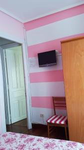 1 dormitorio con una pared de rayas de color rosa y blanco en Pension Martinez, en Bilbao