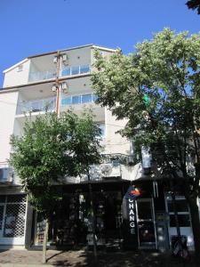 a tall white building with trees in front of it at Central Guesthouse in Nesebar