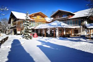 a building with a christmas tree in the snow at Landhotel Böld Oberammergau in Oberammergau