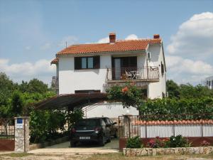 a house with a car parked in front of it at Apartmani Dragovic in Brodarica