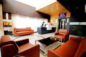 a lobby with orange chairs and a man at a counter at Pinnacle by Click Hotels, Lucknow in Lucknow