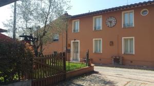 una casa naranja con una valla y un reloj en Ulivo Della Querce, en Querce
