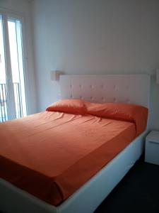 a bedroom with a bed with an orange comforter and a window at Residence Villa Gori in Rimini +44 photos