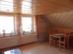 a dining room with a table and two windows at Wohnung Kronacher in Stadtsteinach
