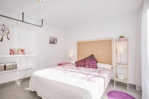 Dormitorio blanco con cama y almohada morada en Flateli Montjuïc, en Girona