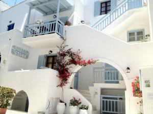 a white building with white stairs and red flowers at Sigma Studios on The Beach in Naxos Chora