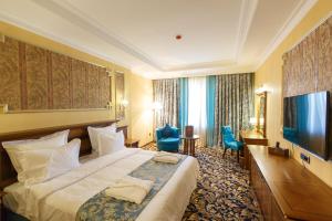 Habitación de hotel con cama y TV de pantalla plana. en Sultan Palace Hotel en Atyraū