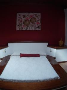 a bedroom with a large bed with a red wall at Vivienda vacacional Finca Ribera De Cortes in Nazaret