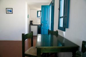 a dining room table with two chairs and a blue door at Oias Sunset in Oia